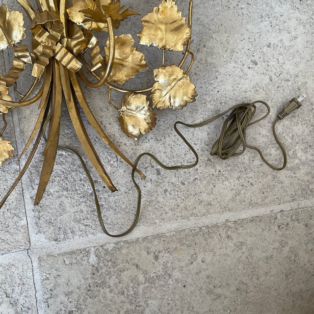 Pair of two-light gilt metal wall sconces featuring grapevine and wheat sheaf motifs tied with ribbon details. Gold leaf...