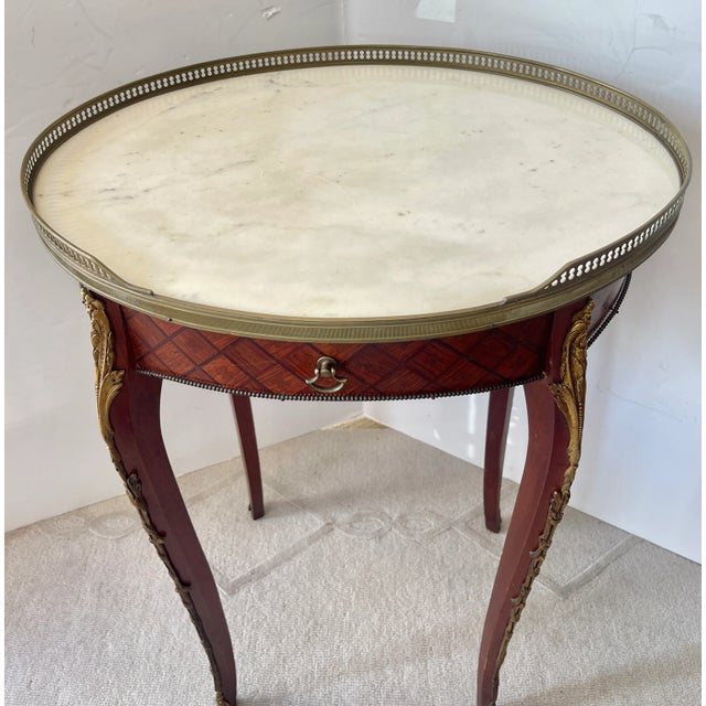 Just in, this charming French Wood Marquetry gueridon side table with a Brass Gallery and original White Marble Top, Early...