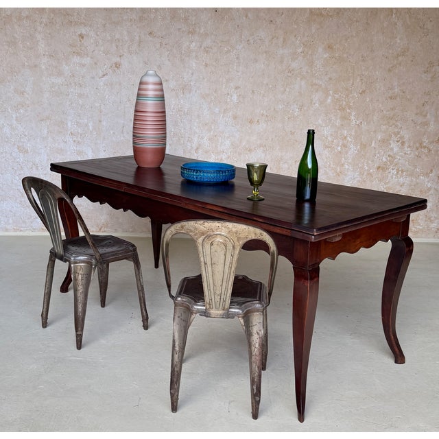 This early 20th century French walnut farm table presents a refined provincial silhouette, distinguished by elegantly...