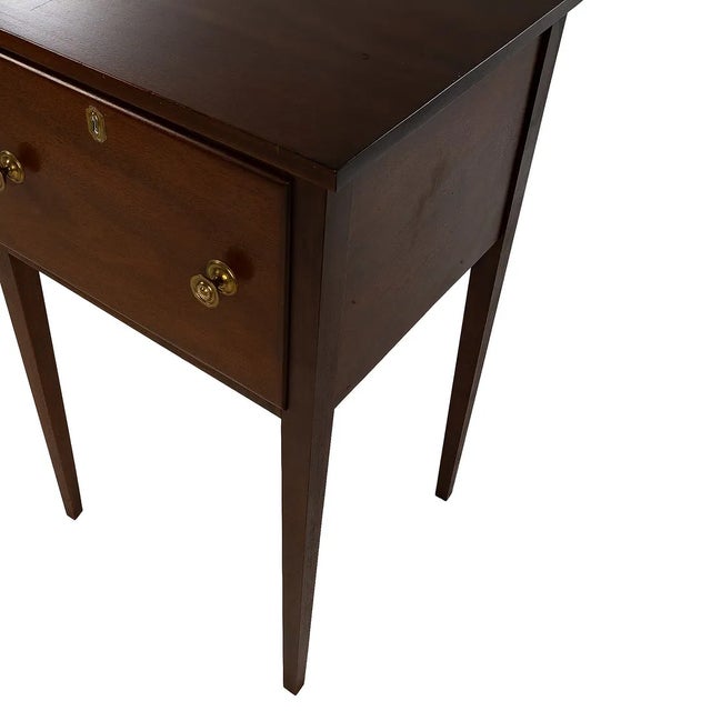 Hepplewhite style huntboard in mahogany. Rectangular top over a three-drawer case. Two larger drawers flank a smaller...