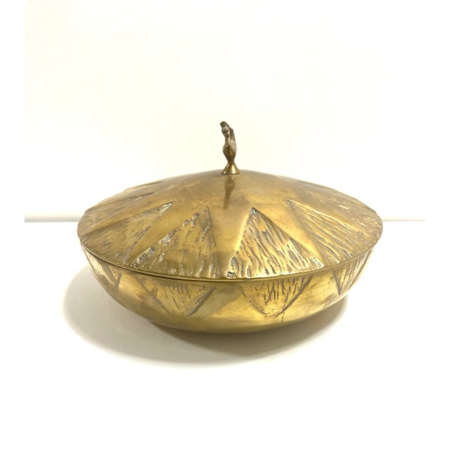 A sculptural Hollywood Regency brass covered bowl featuring a radiant starburst design and elegant swan finial. This...