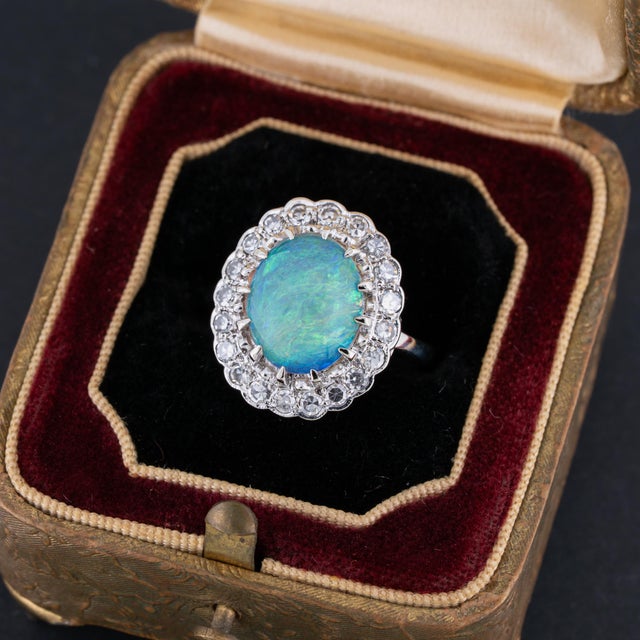 Vintage opal and diamond ring featuring a high quality natural Australian crystal opal oval cabochon accented by a halo of...
