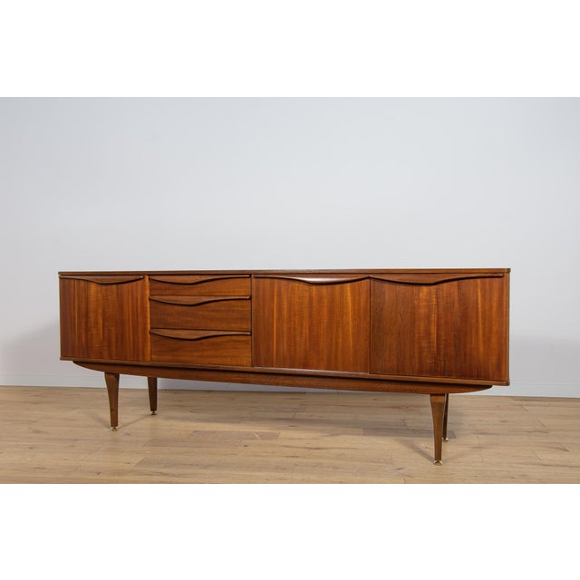 This mid-century sideboard in teak was produced in Great Britain by Stonehill in the 1960s. The chest of drawers has...