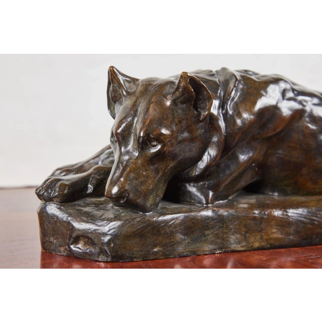 Sensitively rendered, hand-cast, signed bronze sculpture of a resting dog on a naturalistic base of the same by listed...