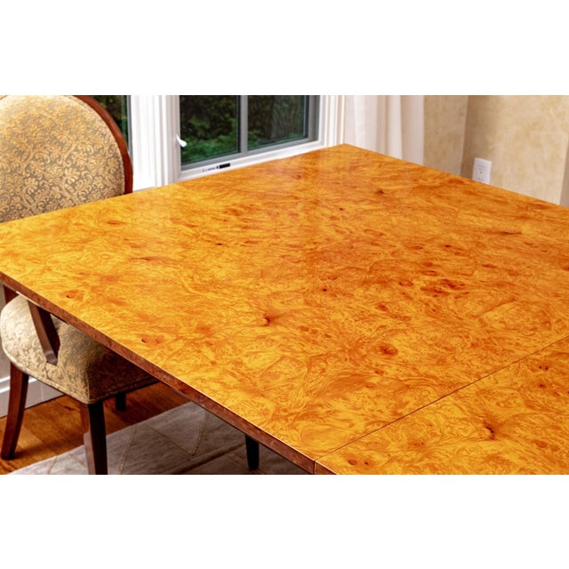 A stunning custom Art Deco style rectangular dining table in a highly polished bird’s-eye burl wood maple with a warm...