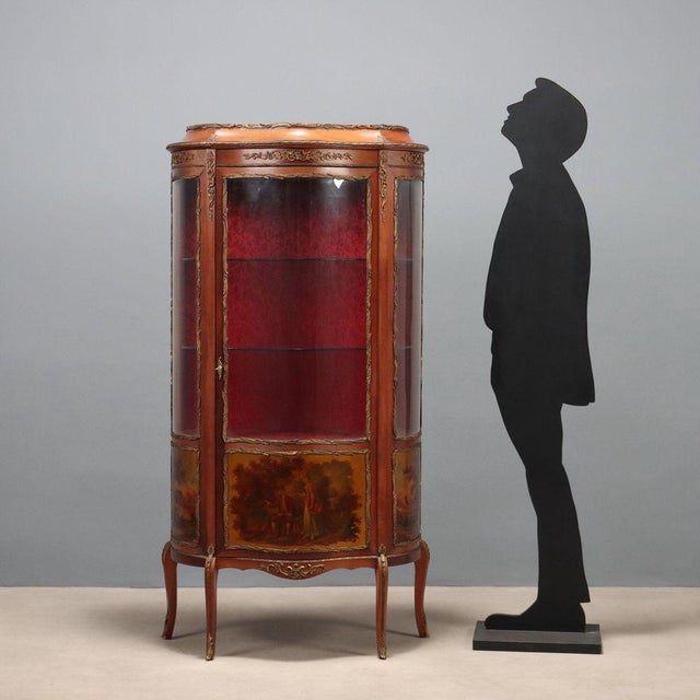 A late Baroque-style mahogany display cabinet. The curved front and sides feature glass panes at the top and painted...