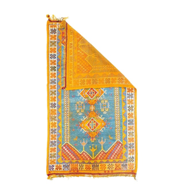 This vintage Rabat area rustic rug shows a partitioned and pointed sky blue field decorated with pendant jewelry, nested...