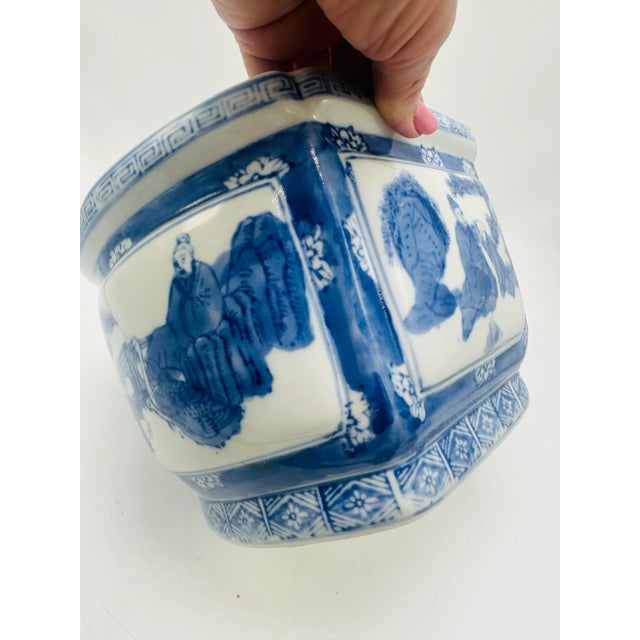 This is a traditional blue-and-white ceramic planter or pot, featuring intricate designs and cultural motifs: • Material:...