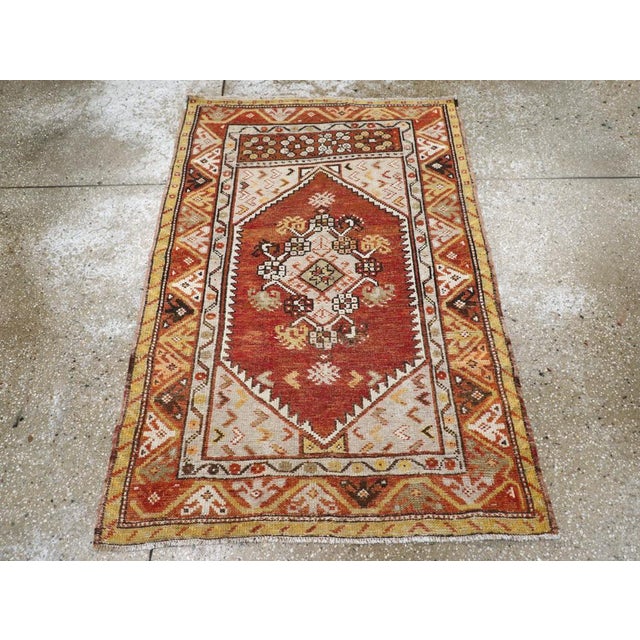A vintage Turkish Anatolian throw rug. A lozenge medallion with carnation edging is set on a red field within a multi-...