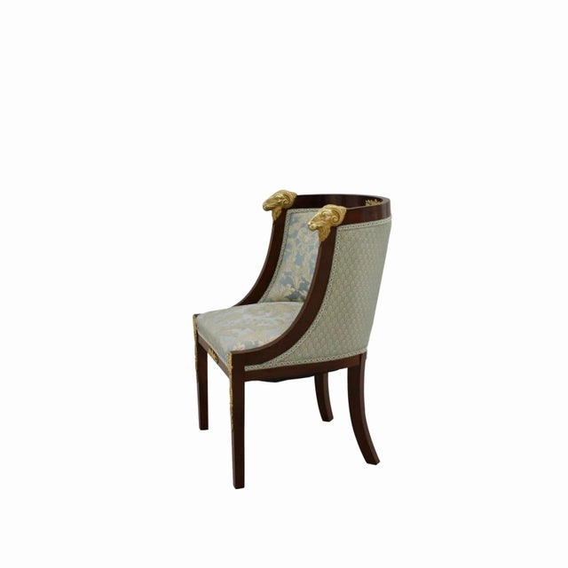 Pair of Empire armchairs with handles in the form of bronze rams heads. hey represent a semi-cylindrical volume with...