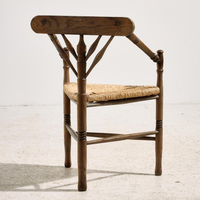 Three-legged oak armchair from the 1930s. The chair features precise details with a woven paper cord seat. with some...