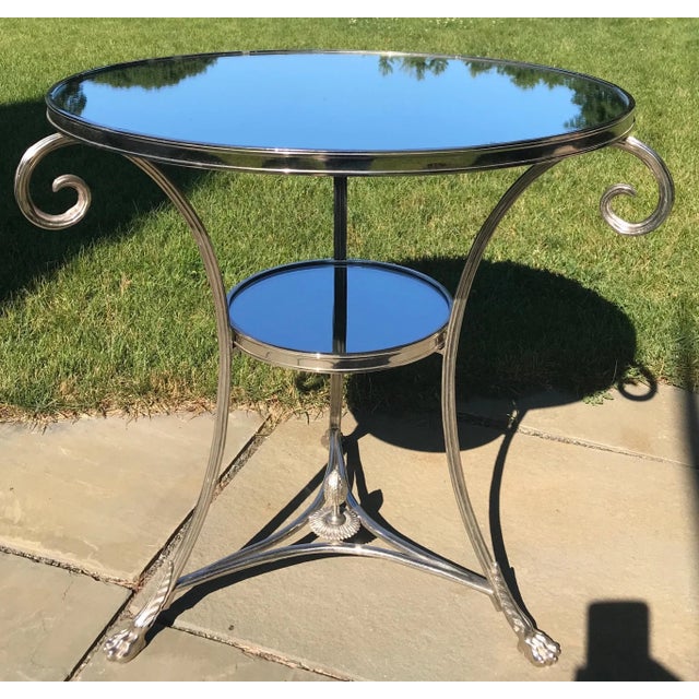 A wonderful French neoclassical round chrome plated bronze gueridon with mirror top. Scroll arms ascent the sides ending...