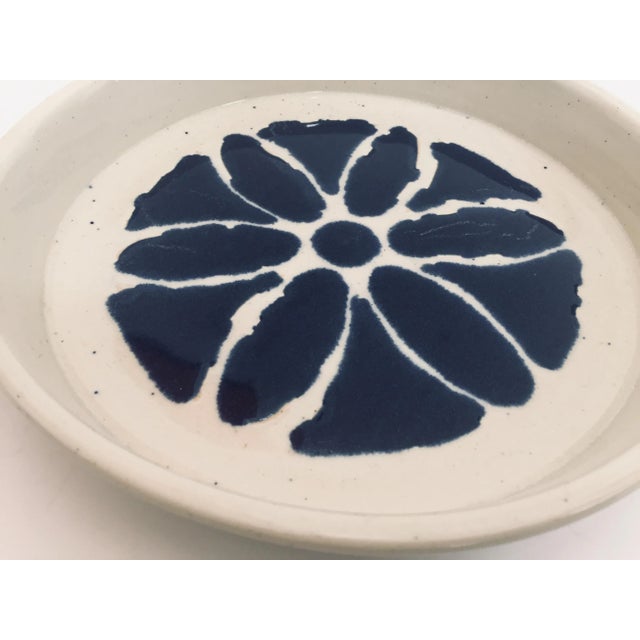 Wheel thrown pottery glazed with a white glaze decorated with a hand painted blue flower pattern. This is a one of a kind...
