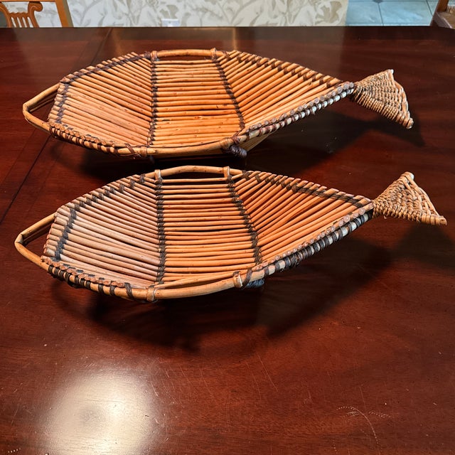 A pair of vintage rattan and bamboo fish baskets. The larger one measures 27” total length, 11.5” wide, and 4.5” high. The...