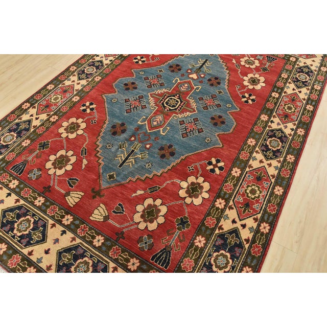 A tribal Caucasian Kazak rug hand-knotted with fine wool on a cotton foundation. This oriental rug features a central...