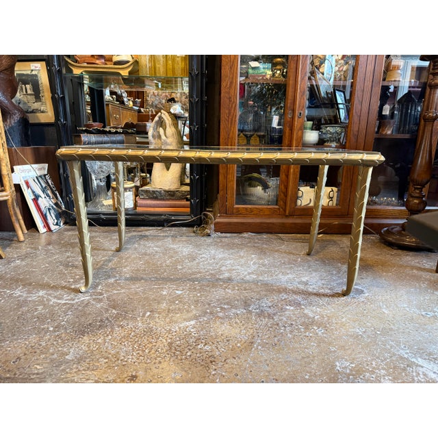 A vintage brass coffee table featuring sculptural overlapping leaf detailing, designed in the style of Maison Jansen. The...
