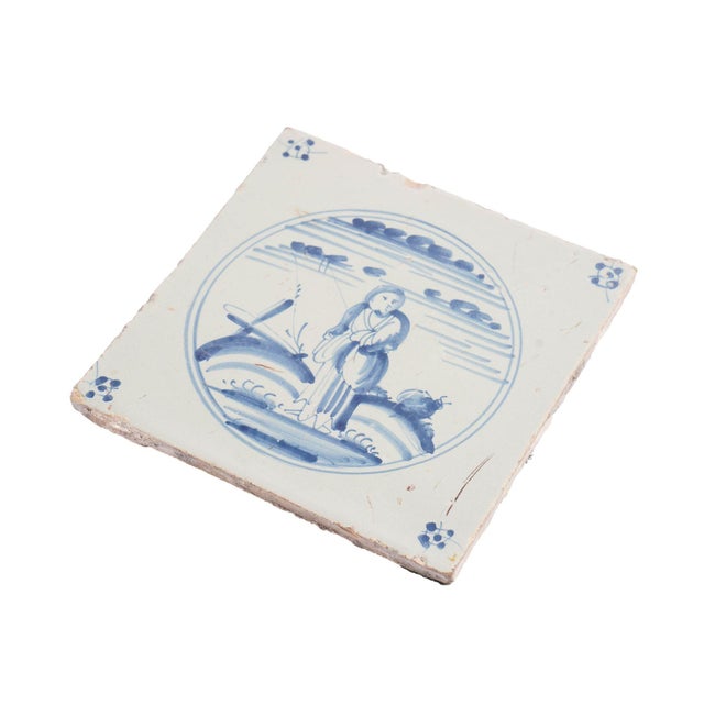 Single Delft tile of a girl in a dirndl skirt with robe a la polonaise, in cobalt underglaze blue. Backed with a felt pad...