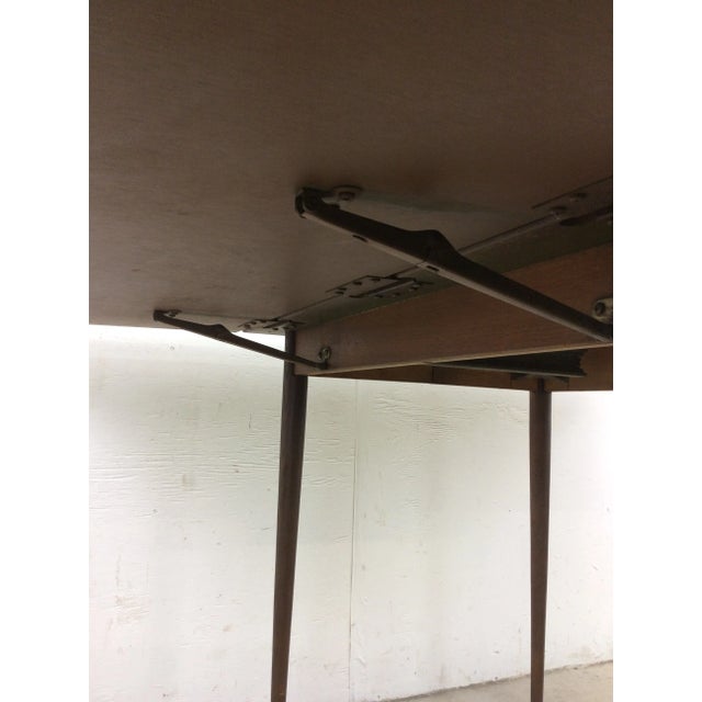 This mid century modern dining table features drop leaf design, durable formica top with faux woodgrain, two additional...