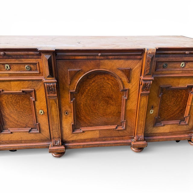 This is a magnificent Italian antique walnut sideboard featuring rich burl wood panels, carved column details, and its...
