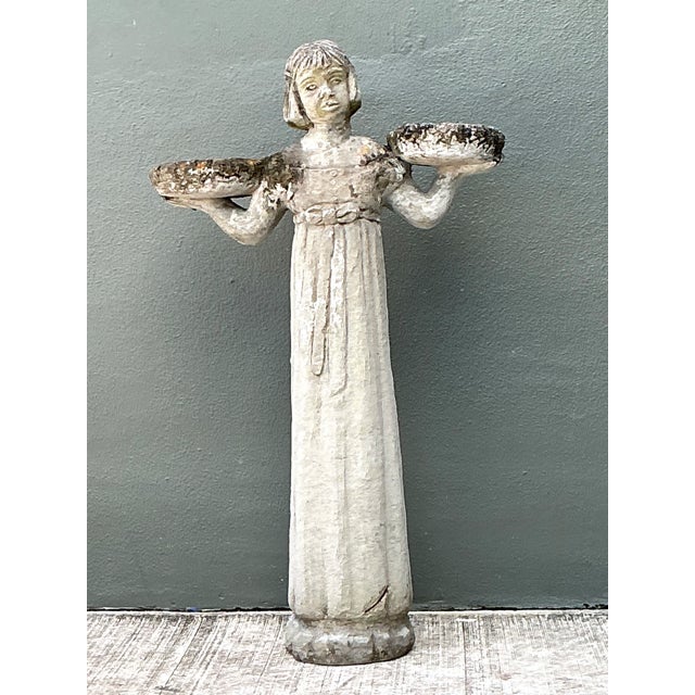 This vintage garden figure is cast in stone and stands with a calm, classical presence. The draped figure holds two...
