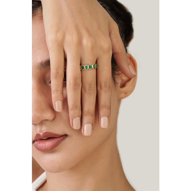 This solitaire bezel-set ring features a 1.64-carat natural oval-cut emerald set in 18K yellow gold. The emerald measures...