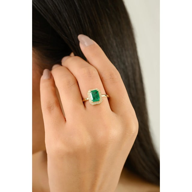 This Certified 1.53 Ct Emerald and Diamond Halo Ring features a vibrant emerald at its center, cut in a classic emerald...