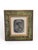 Decorative bronze relief plaque depicting a stylized human face, presented within an elegant frame. The sculpture is...