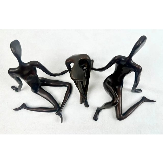 A refined set of three limited-edition bronze sculptures depicting elongated seated female figures, each signed by the...