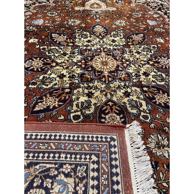 A substantial hand-knotted Ghom rug measuring 345 × 255 cm. It features warm brown shades with a detailed multicolour...