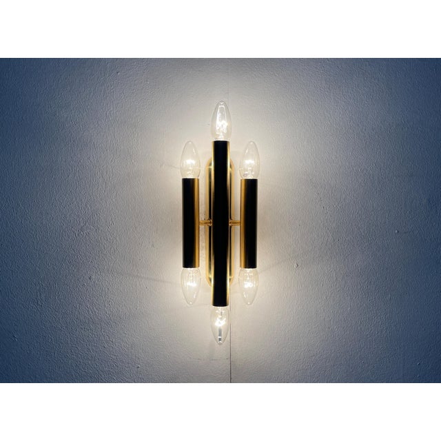 Imposing wall light in brass. Three parallel cylinders with sockets at the top and bottom ends. The cylinders are mounted...