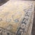 A contemporary hand-knotted Turkish Oushak rug featuring a warm golden beige field accented by large-scale floral motifs...