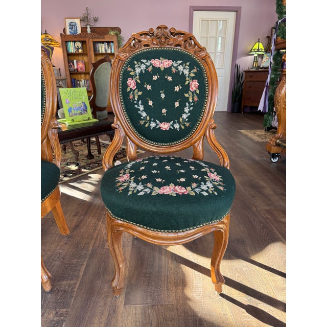 Pair of victorian chairs with carved wood frame & dark green, hand-stiched floral needlepoint upholstery. Both chairs are...