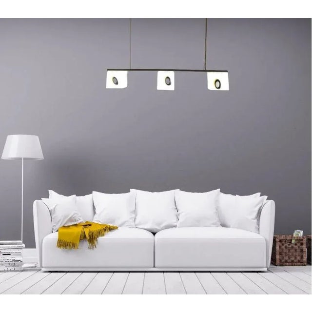 Height-adjustable suspension lamp with steel cable and offset light source, from which hangs a rectangular matt chrome-...