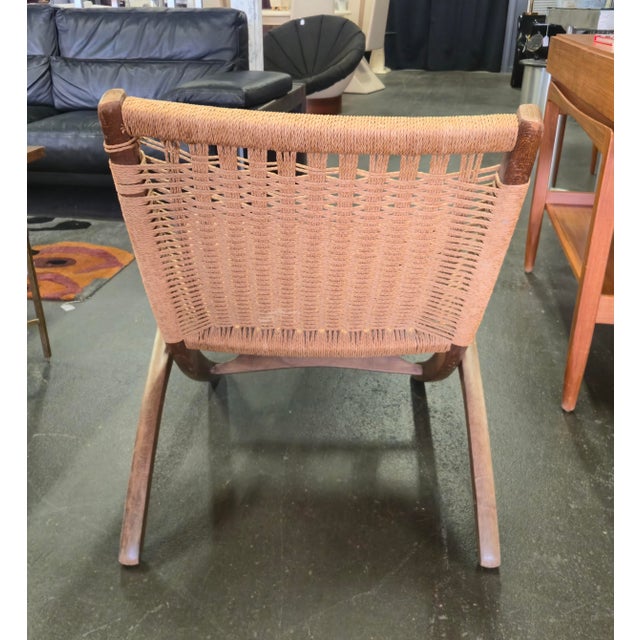 Low profile and portable folding scissor frame accent chair has a wooden frame with woven cord seating and backing. Folds...
