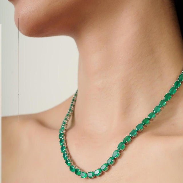 A refined green onyx tennis necklace crafted in 925 sterling silver, featuring oval-cut gemstones measuring 5 x 7 mm with...