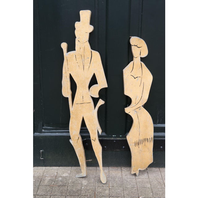 Pair of 1890s style figures of a man in a top hat with a walking stick and a svelte woman made of metal form France. Woman...