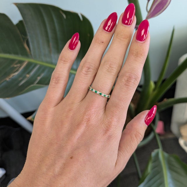 Eight earth-mined diamonds alternate with seven natural emeralds around this solid 14K yellow gold band, a rhythmic play...