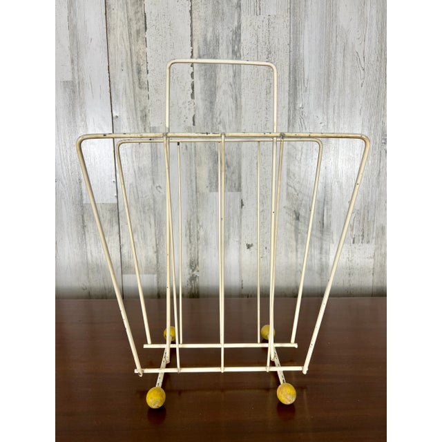 Modernist lacquered metal with wood ball feet magazine rack very space age.