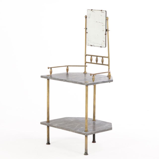 A charming late-19th-century French brass vanity featuring two marble shelves and an adjustable beveled mirror with...