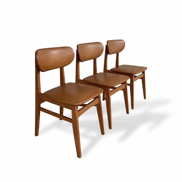A stylish set of three Schreiber dining chairs, showcasing classic mid century proportions with softly shaped backs and...