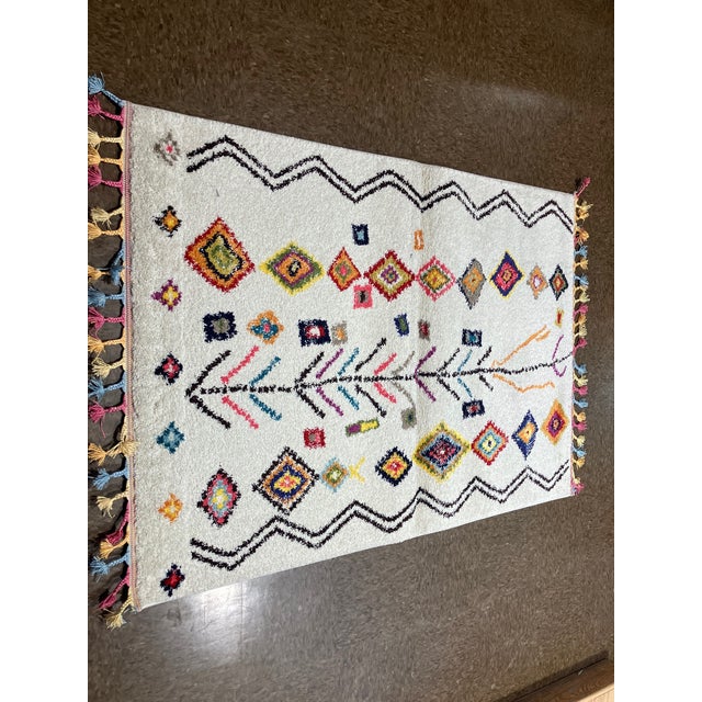 Machine-made Turkish rug in polypropylene featuring a Moroccan-inspired design with a central linear motif and scattered...