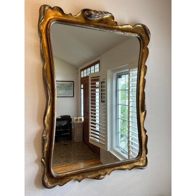 An exceptional mid-20th century Italian giltwood mirror featuring a dramatic sculptural frame evocative of the celebrated...