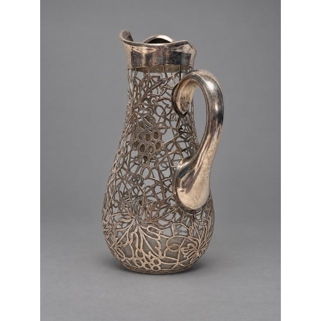 An American Art Nouveau pitcher, circa 1890–1910, combining clear glass with an elaborate fine-silver overlay, by Alvin...