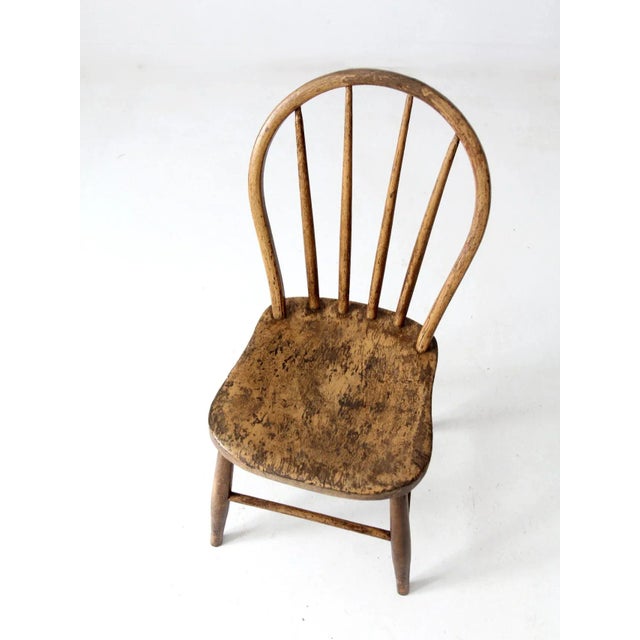 Antique bow-back Windsor chair featuring a classic farmhouse silhouette. Crafted with splayed wooden legs and a spindle-...