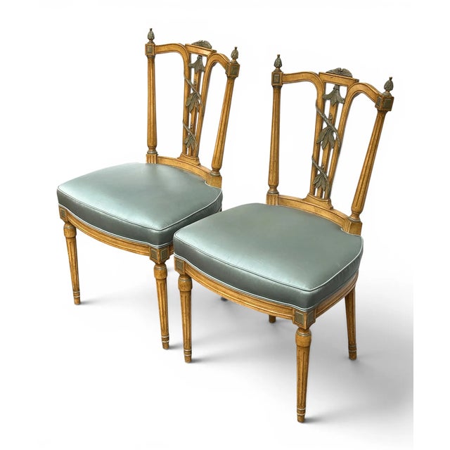 These Louis XVI style side or accent chairs have flora and vine carvings, fluted legs, and silk-like upholstery. Each...