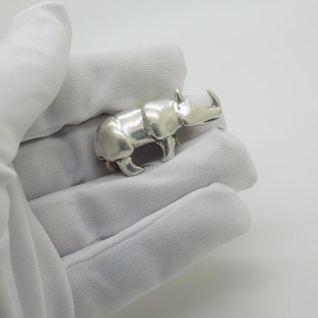 This vintage silver wildlife sculpture depicts a rhinoceros, crafted as a desktop display piece, paperweight, or cabinet...