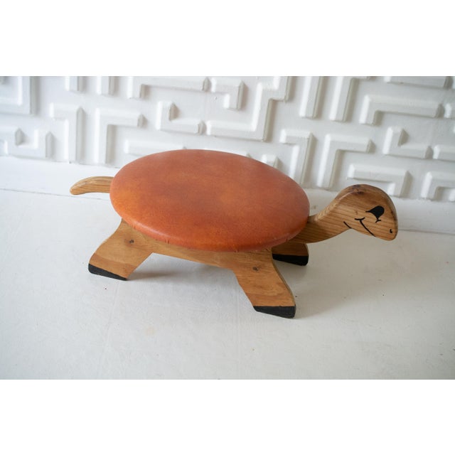 This listing is for a 1960s vintage, handmade wooden turtle footstool. It features an burnt orange "faux leather" vinyl...