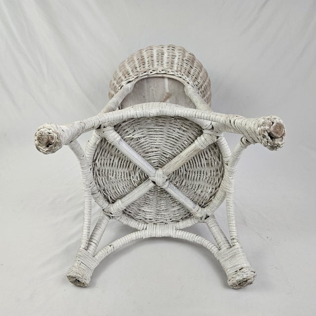 Charming vintage white wicker planter stand featuring a decorative woven design and convenient lower shelf for added...