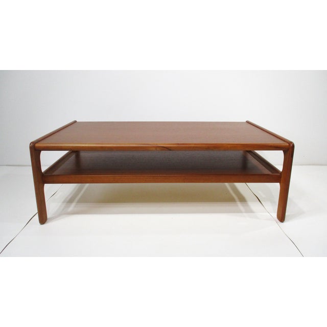 A larger sized sturdy teak wood coffee table with lower functional storage shelve and rounded sculptural legs . Designed...
