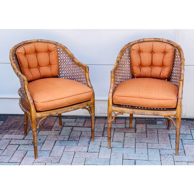 Gorgeous pair of 29 th c faux bamboo tub chairs with cane. Custom upholstery in burnt orange. McGuire style.
